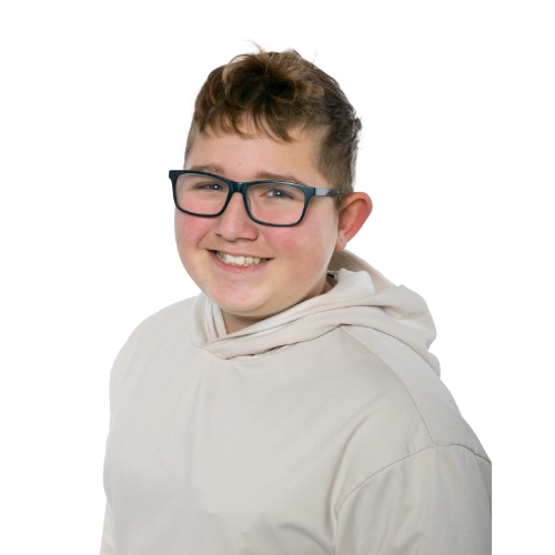 Portrait of Kayden, a 13-year-old smiling and wearing glasses and a light-coloured hoodie against a light background
