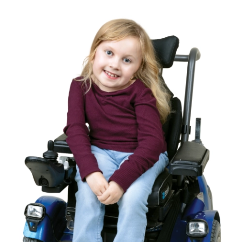 Portrait of Ellis, an 11-year-old smiling while seated in a powerchair against a light background