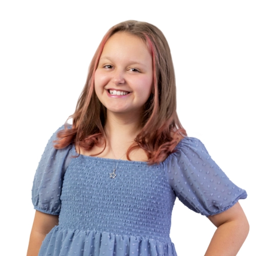 Portrait of Karlee, a 10-year-old smiling in a blue dress against a light background