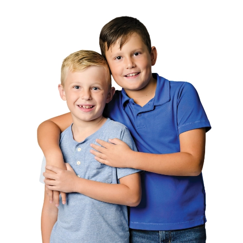 Portrait of brothers Lochlan and Colton, ages 8 and 10, smiling together against a light background