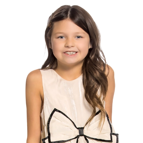 Portrait of Ireland, a 9-year-old girl smiling in a cream dress against a light background