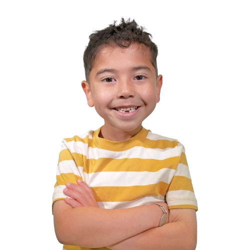 Portrait of Caleb, a 7-year-old smiling in a yellow and white striped shirt against a light background